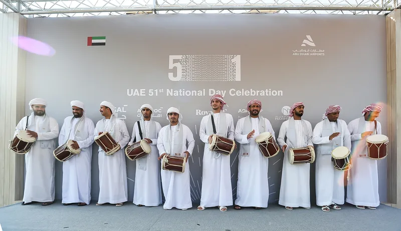 Traditional Emirati drummers performing in white kanduras on covered outdoor garden stage in Abu Dhabi