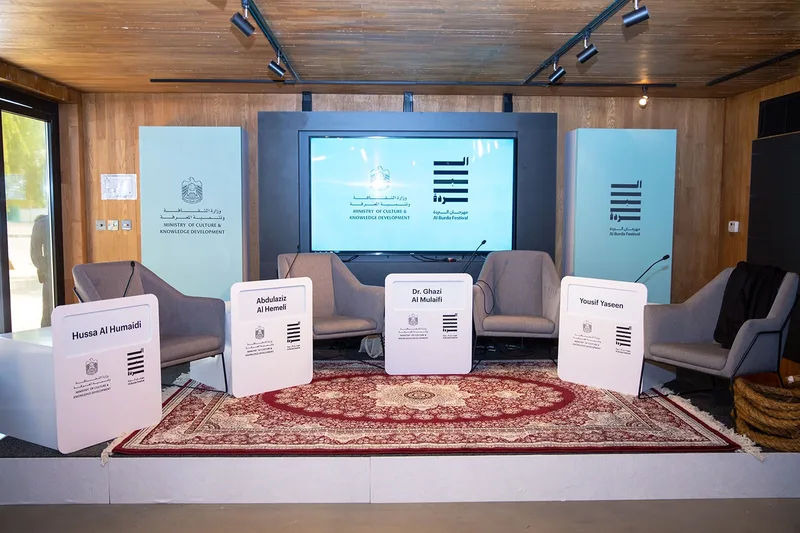 Al Burda Festival panel discussion stage with four armchairs and branded speaker name panels
