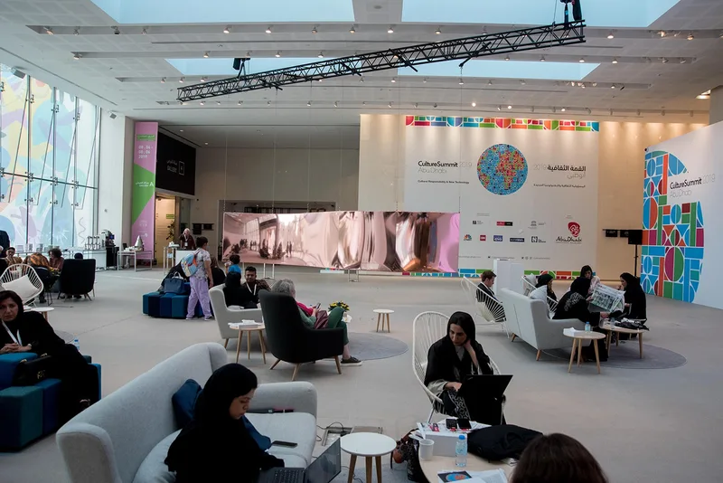 International cultural delegates seated at curved discussion tables inside main summit hall