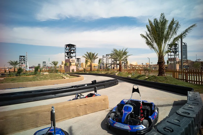 Outdoor go-karting track with safety barriers and palm trees constructed for family entertainment at Diriyah Oasis