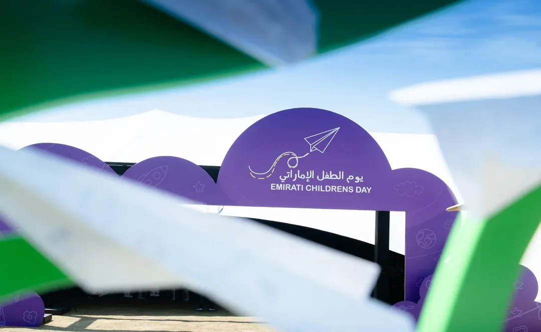 Emirati Children’s Day entrance arch with purple cloud-shaped branding, framed by blurred UAE flag decorations