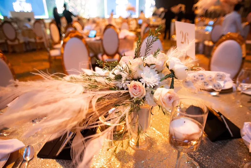 Evolution Events ballroom setup with gold tables, oval chairs and dramatic lighting.