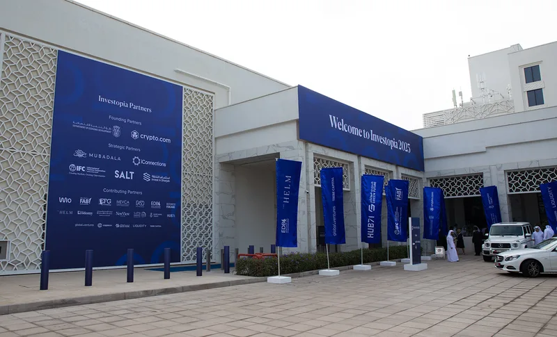 Evolution Events Investopia entrance branding with partner wall, welcome signage and sponsor flags