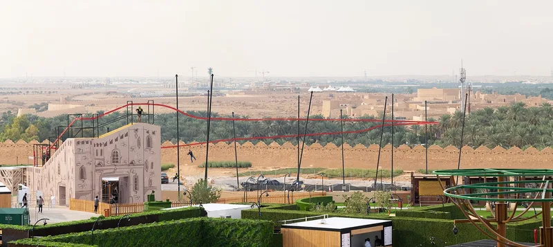 Zip line attraction stretching across festival grounds with traditional mudbrick style launch tower in Riyadh