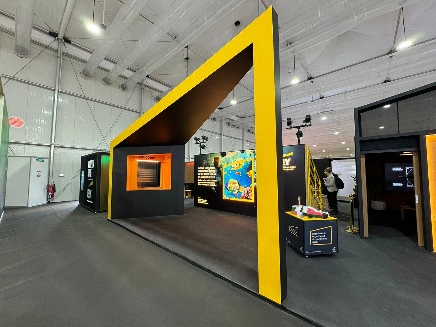 Wide-angle shot of busy EY exhibition booth at COP28 Dubai attracting global delegates