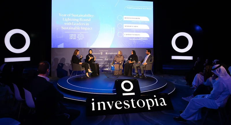 Investopia sustainability panel on a circular stage with LED screen and audience seating